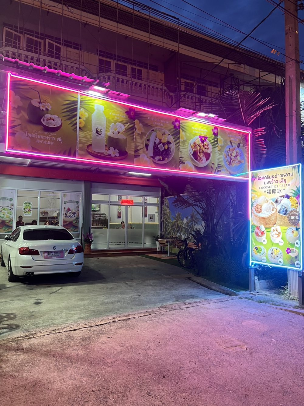หน้าร้านไอศครีมมะพร้าว เจ๊ยุ ยามค่ำ ป้ายไฟนีออนและป้ายเมนูริมถนนราชพฤกษ์ บางกร่าง นนทบุรี